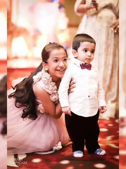 An older sister peeks out from behind her little brother during a family event. We are always looking for these cute, candid interactions.