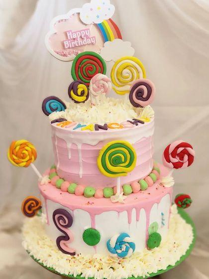 A two-tier candyland cake. This fun design is overloaded with lollipops, candies, and a white chocolate drip, perfect for a sweet-themed party.