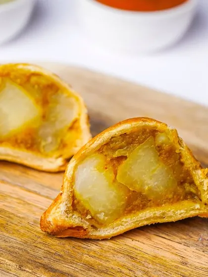 A crispy samosa cut in half to reveal the spiced potato filling inside. This detailed shot is excellent for a menu, as it shows customers exactly what to expect.