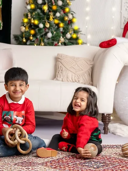 The smells of Christmas are the smells of childhood. Two siblings share a laugh while playing with wooden toys in our festive setup.