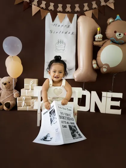 A bright and happy shot of the baby holding his birthday newspaper, smiling from ear to ear.