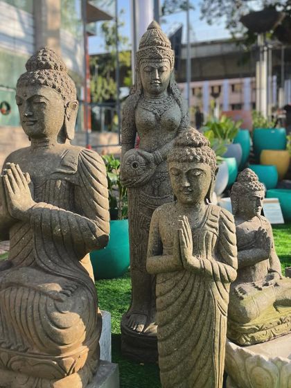 A selection of our stone Buddha and Balinese doll statues on display. You can see the variety in poses, from the seated meditating Buddha to the standing figure with hands in a prayer gesture.