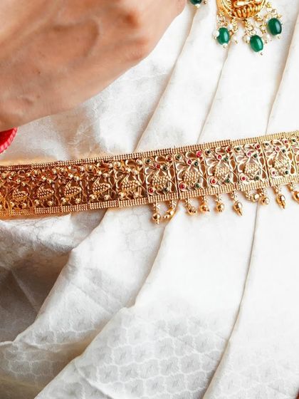 This image highlights the traditional gold waist belt, or 'vaddanam', showing its detailed pattern against the simple white saree. It's another example of how we capture key fashion elements for commercial clients.