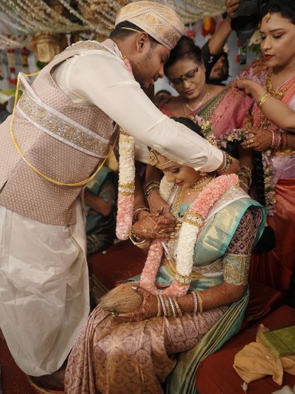 The groom performing a ritual for the bride during their traditional wedding ceremony.