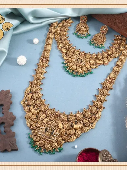 This full bridal set features two layered temple necklaces with intricate peacock and deity motifs. The matching jhumkis complete the look, offering a comprehensive and high-demand product for your bridal section.