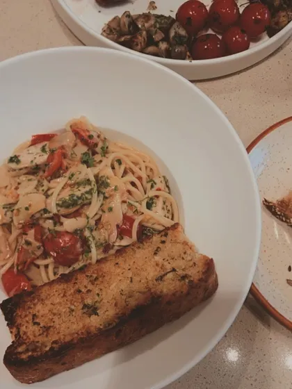 A classic spaghetti dish tossed with chicken, cherry tomatoes, and fresh herbs, served with a side of toasted garlic bread. A simple, satisfying, and delicious meal.