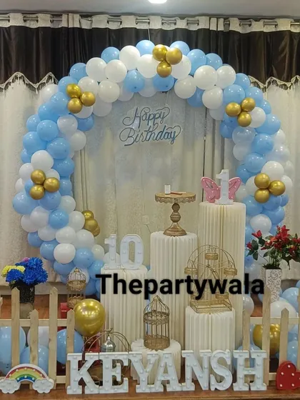 A simple and elegant ring decoration with blue, white, and gold balloons. The setup is perfect for a 10th birthday party.