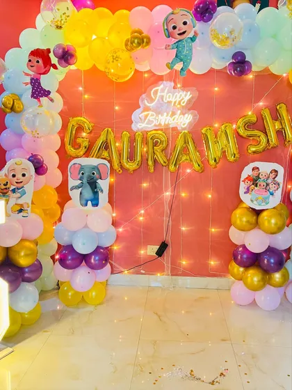 A close-up on the Cocomelon backdrop with the neon 'Happy Birthday' sign.