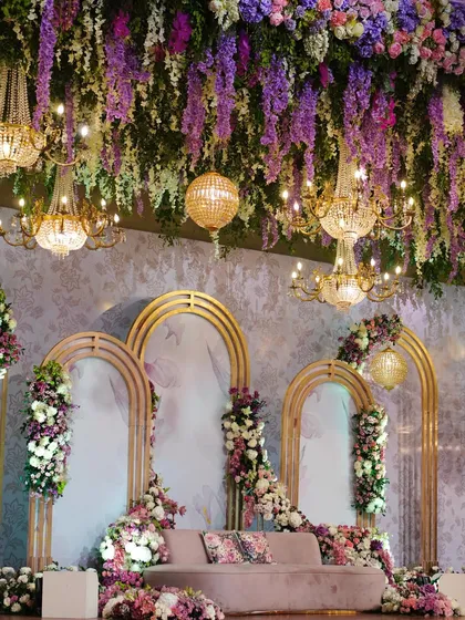 A grand view of the purple-themed stage. Golden arches, a ceiling of hanging wisteria, and magnificent chandeliers create a setting of pure opulence and modern royalty.