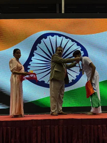A proud moment on the international podium. An official places the silver medal around Shandai Tanishq Jain's neck, recognizing his achievement at the Asian Goju-Ryu Tournament.