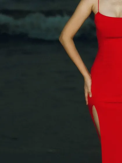 The vibrant red dress against the dark, twilight beach is a stunning combination. This is just a teaser of the dramatic color contrast we captured.