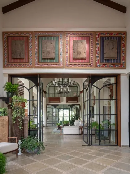 A wide shot of the entrance, showcasing the impressive scale, the collection of Naga art panels, and the clear line of sight through the living room to the pool area, a key client requirement.