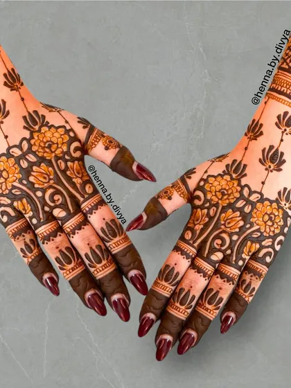 A beautiful back-of-hand design featuring a vertical line of lotus and floral motifs. The dark, filled-in fingertips provide a striking contrast to the delicate pattern work.