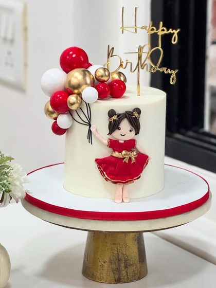 When handcrafted love meets festive colors! This adorable cake features a doll in a red dress holding balloons, perfect for a little one's magical birthday bash.