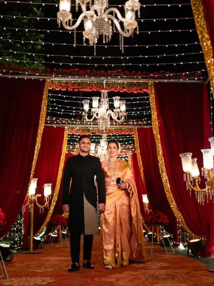 We created a grand, regal entrance for this reception, using rich red drapery, gold accents, and elegant chandeliers. This setup, illuminated by fairy lights and classic candelabras, was designed to make the couple's entrance feel like a royal affair.