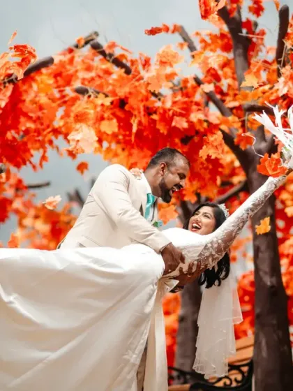 A moment of pure, unscripted laughter during a post-wedding shoot. The vibrant autumn leaves create a stunning backdrop, but it's the couple's genuine joy that makes this photo special.