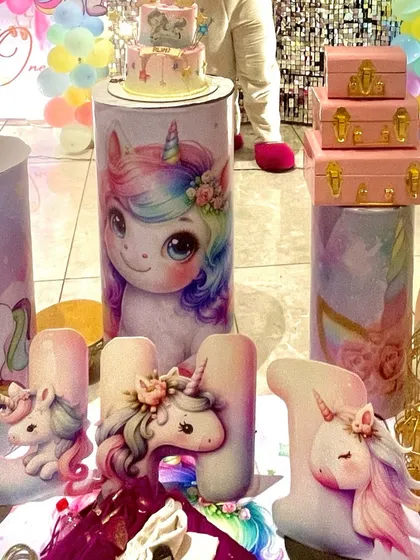 Custom-printed plinths and detailed unicorn-themed letters for the birthday girl's name. The cake is perfectly placed on a matching unicorn pedestal.