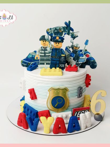 A fun and detailed LEGO police-themed cake for a 6th birthday. This cake is decorated with LEGO police officers, a patrol car, and a shield, all crafted from fondant for an adventurous celebration.