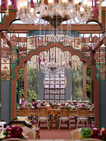 A view through ornate, carved arches into a beautifully set dining area. I use layering in my designs to create depth and a sense of discovery as guests move through the space.