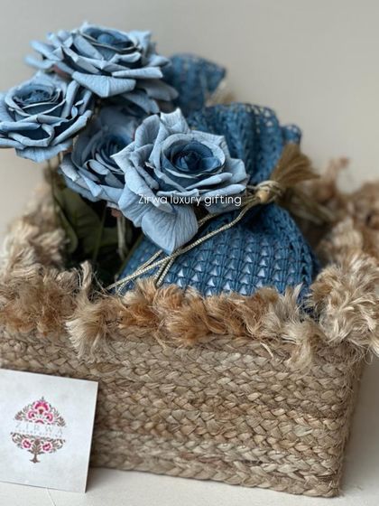 Another style of floral gift basket, this one with a rustic, frayed jute trim. The blue sola wood flowers and matching potli create a coordinated and charming look.