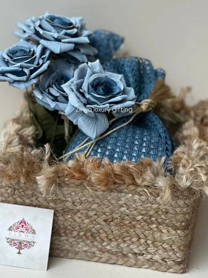 Another style of floral gift basket, this one with a rustic, frayed jute trim. The blue sola wood flowers and matching potli create a coordinated and charming look.