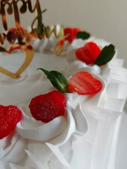 A close-up view of the heart-shaped strawberries and intricate piping on this lovely anniversary cake.