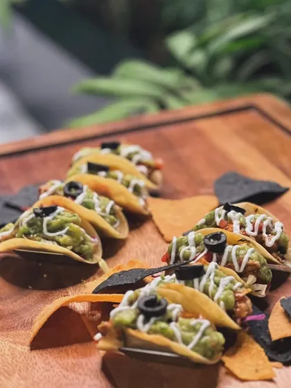 Another view of my guacamole-loaded mini tacos, presented on a rustic wooden board with assorted tortilla chips. The presentation is as important as the taste.