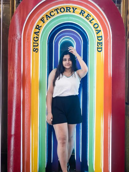 A guest posing at the entrance of Sugar Factory Reloaded.