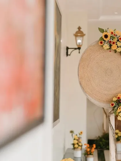 A decor detail featuring a woven jute disc adorned with a crescent of yellow flowers.