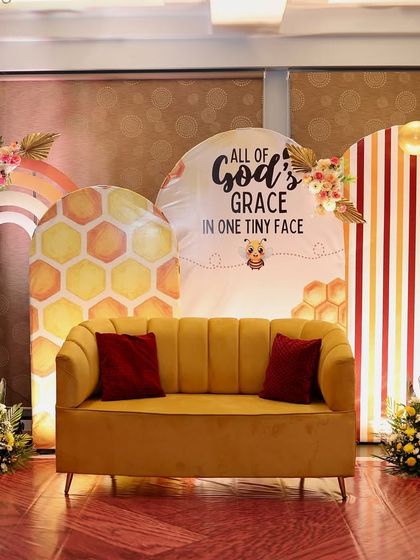 A wider view of the bee-themed naming ceremony decoration. The arrangement of the backdrops, balloon arches, and floral accents creates a full and festive stage for the celebration.