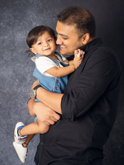 A father holds his smiling child close. We aim to capture the warmth and affection in every family portrait we take.