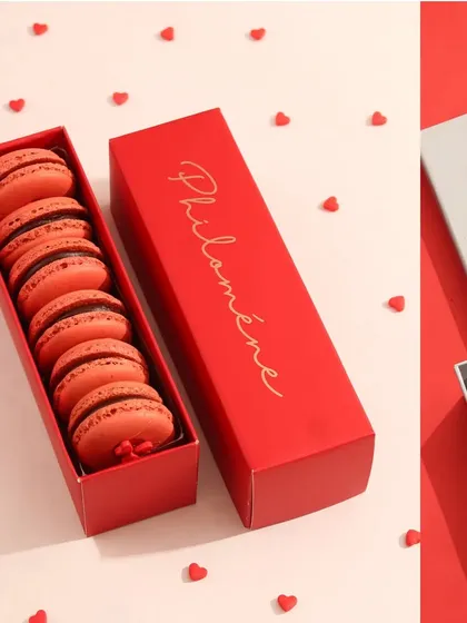 This shot focuses on the packaging and presentation of a Valentine's macaron box. The neat arrangement and heart confetti emphasize the product as a perfect, elegant gift.