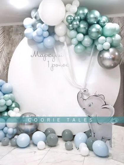 A minimal and modern baby shower with a cute elephant accent. The clean white backdrop is framed by a stylish arrangement of metallic and pastel blue balloons, creating a simple yet impactful design.