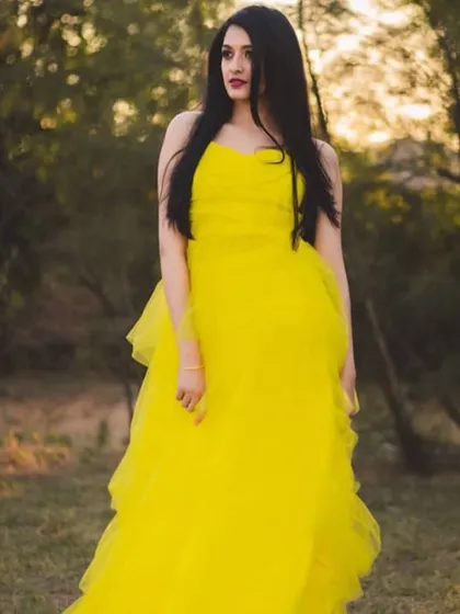 A candid-style portrait of the model in the yellow gown, looking away from the camera for a natural, editorial feel.