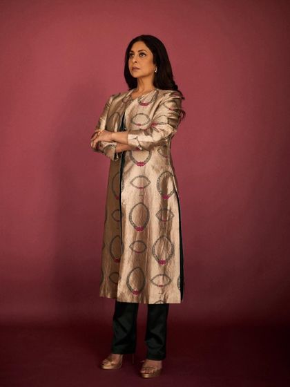 The full look, pairing the long brocade jacket with simple dark trousers for a balanced and sophisticated ensemble.