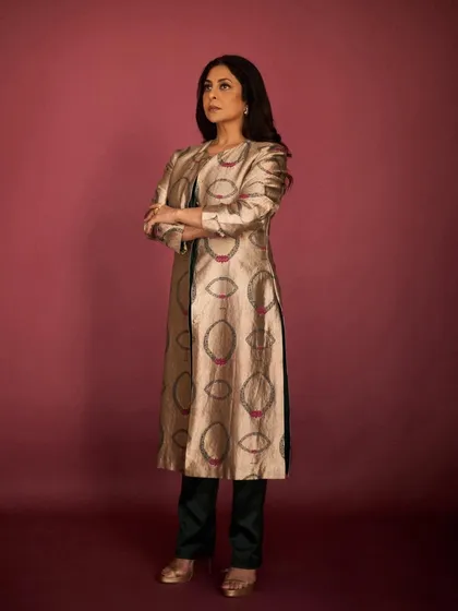 The full look, pairing the long brocade jacket with simple dark trousers for a balanced and sophisticated ensemble.
