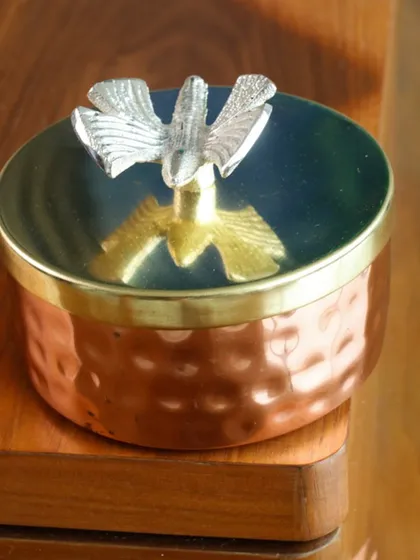 A unique candle in a hammered copper bowl with a dual-tone bird motif on the lid. This piece is a perfect blend of artisanal craftsmanship and modern design.