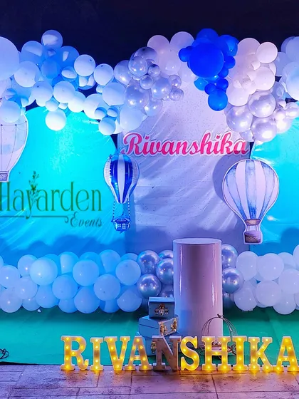 A full view of the hot air balloon themed stage, with marquee letters, a cloud-like balloon garland, and hot air balloon cutouts.