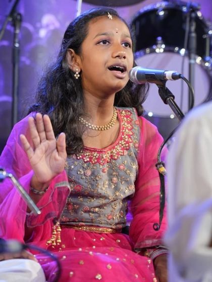 A young girl sings with clarity and poise, showcasing the results of her Carnatic vocal training.