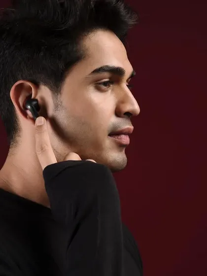 A clean, minimalist studio portrait for Crossbeats audio products. The deep red background creates a moody and sophisticated atmosphere, while the model's profile highlights the sleek design of the in-ear headphones.