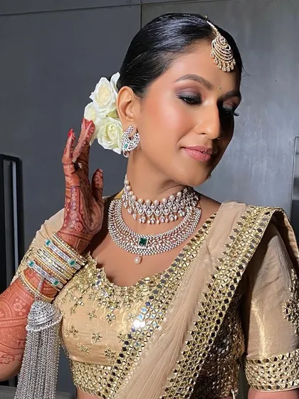 A front-facing view of the elegant bridal look, where the neat bun keeps the focus on the bride's glowing makeup and stunning diamond jewelry.