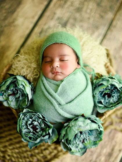 A lovely light green theme, with the baby wrapped and wearing a matching bonnet, surrounded by green peonies.