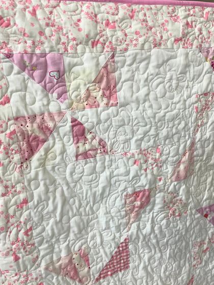 A close-up of the pink baby quilt, showing the floral and Snoopy-themed fabrics.