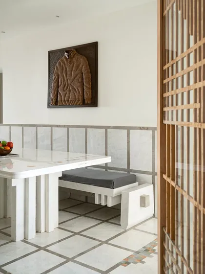 This dining space is a study in geometry and craft. The custom dining table is made of solid stone, with playful, colourful marble inlays. It is paired with a sculpted stone bench, turning everyday meals into a design-led ritual.