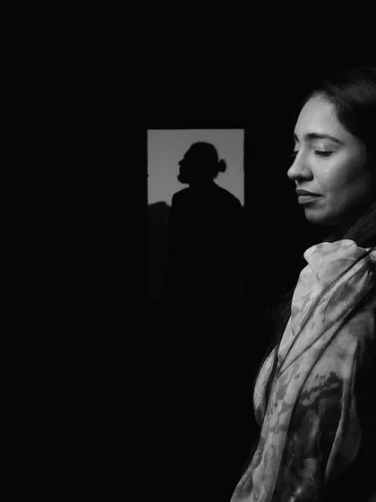 A creative black and white portrait, where the groom's silhouette is reflected in a window as the bride stands in the foreground, creating a layered and thoughtful composition.