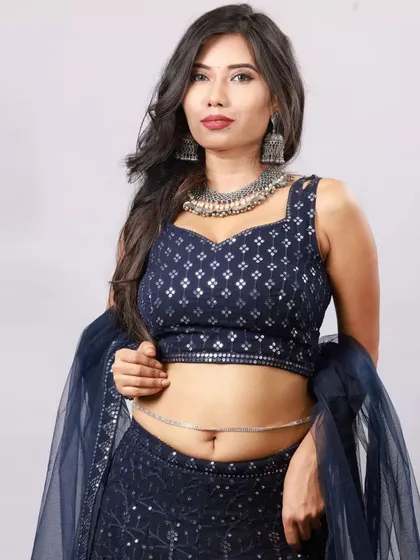 This studio shot emphasizes the modern cut of the lehenga choli and the delicate waist chain. The lighting is set up to define the model's features and the outfit's silhouette.