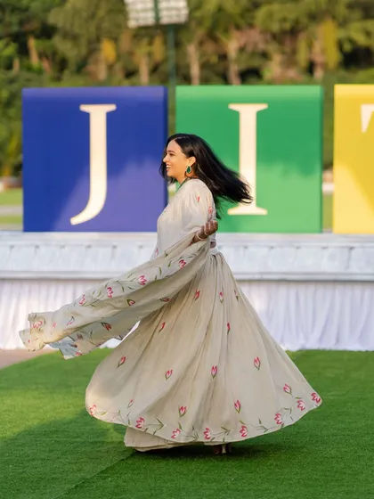 Another twirling shot showing off the flow of my outfit against the large JITO event branding. It captures the grand scale and happy vibe of the community gathering.