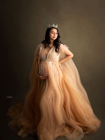 A quiet, royal moment. The mom-to-be looks down at her bump, her crown adding a touch of majesty to the portrait.