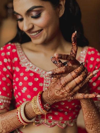 A happy bride admires her henna-covered hands, a quiet moment of joy before the ceremony begins.