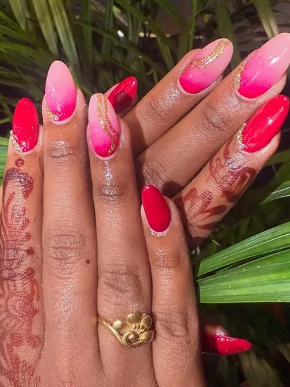 This design shows a beautiful pink-to-red ombre effect on long almond nails. A delicate gold swirl is hand-painted over the top, adding a touch of elegance that catches the light perfectly.